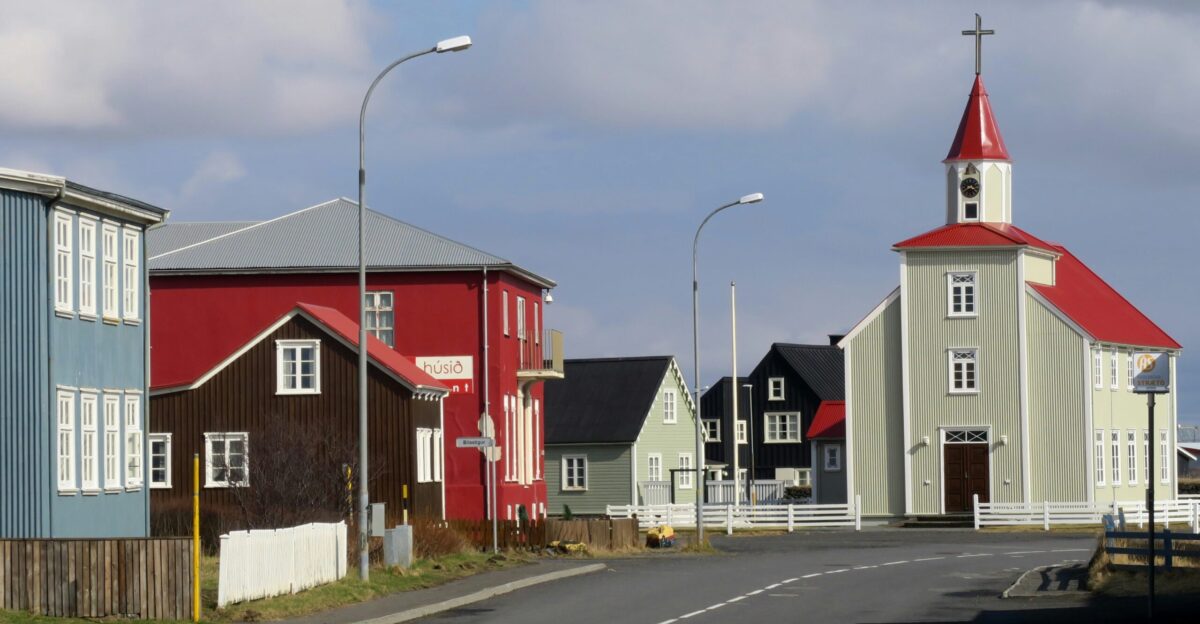 red and white houses beside road under white clouds during daytime