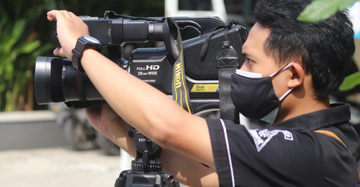 man in black and white t-shirt holding black dslr camera