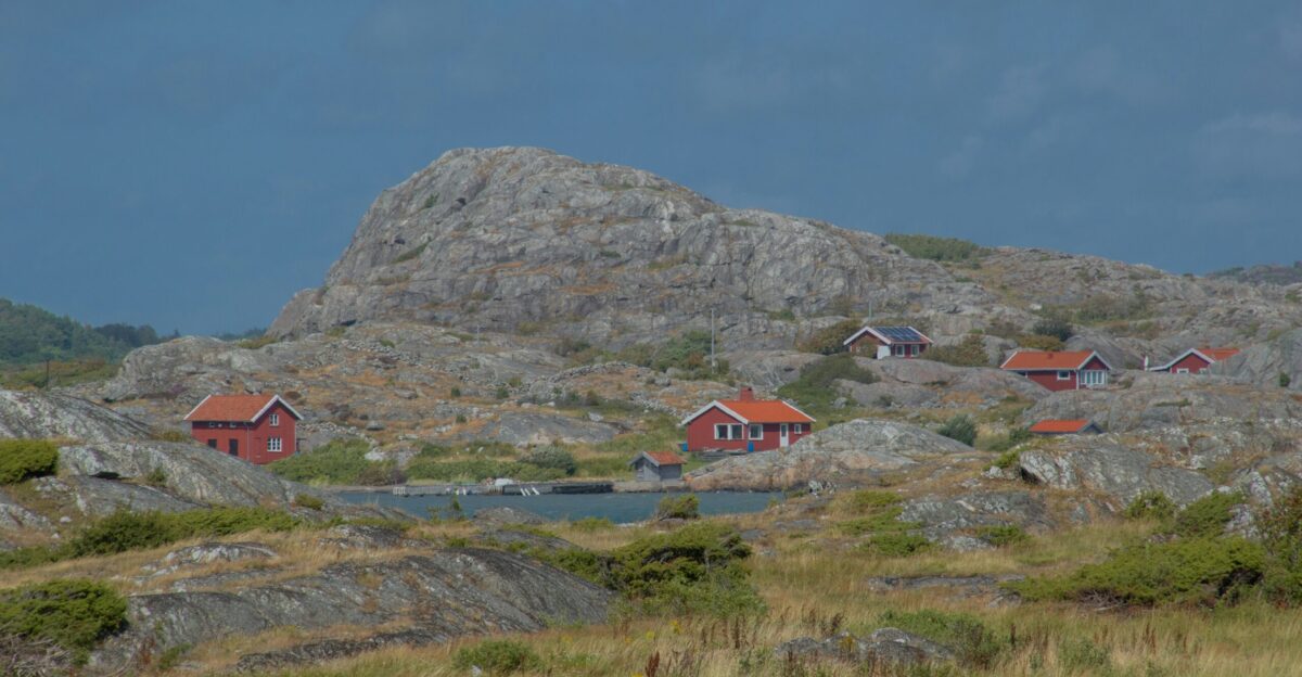 red and white house on green grass field near rocky mountain under blue sky during daytime