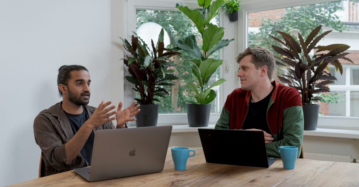 man in red and black crew neck t-shirt using silver macbook