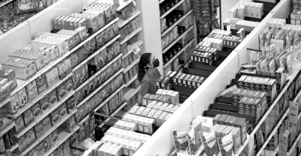 a black and white photo of a woman shopping in a grocery store