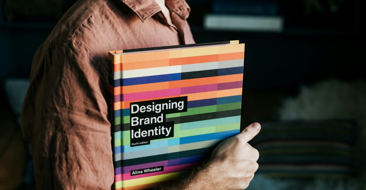 a man holding a book that says designing brand identity