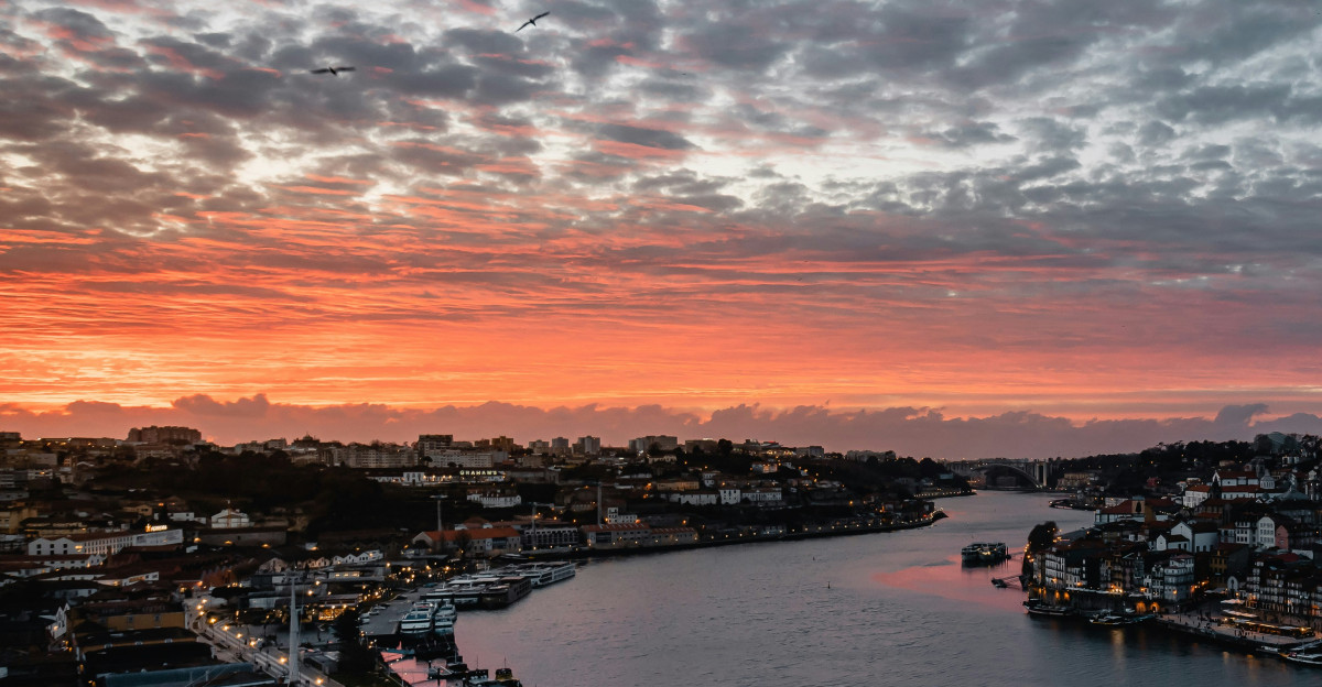 a sunset over a river with a city in the background