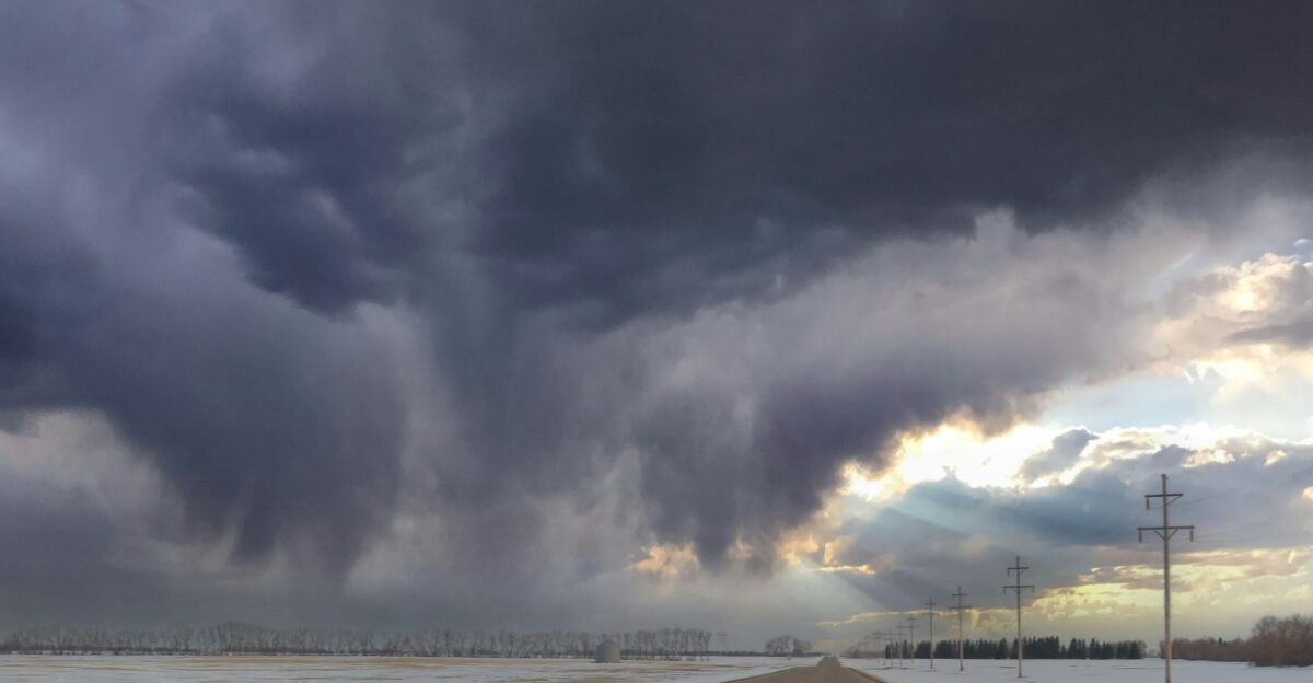 a road with snow on the side and a cloudy sky above