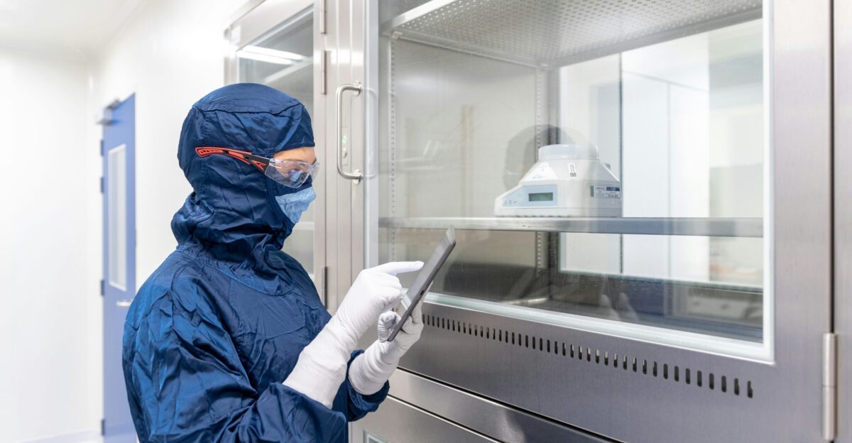 a person in a blue mask and gloves holding a tablet