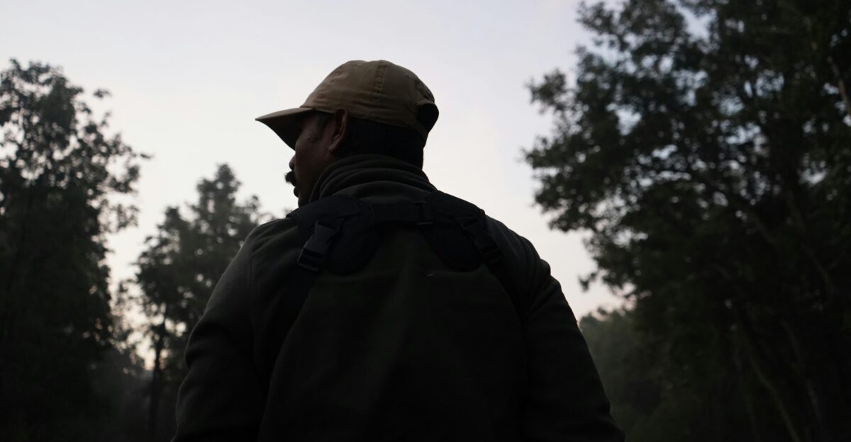 a man standing in a field with trees in the background