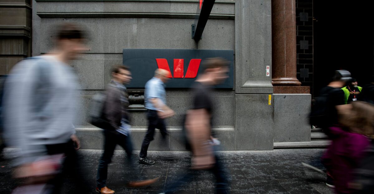 a group of people walking down a street next to a tall building