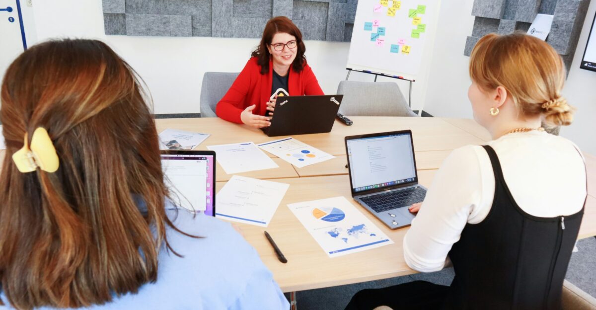 a group of people sitting around a table with laptops
