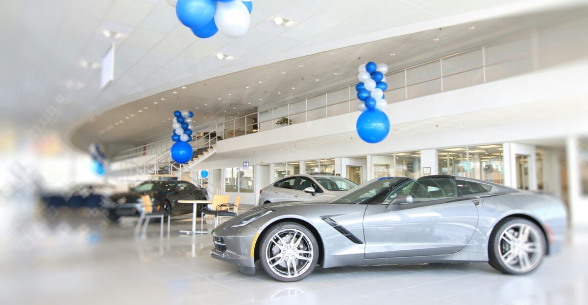 a silver sports car in a showroom with blue and white balloons