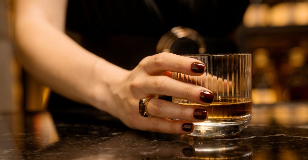 a woman s hand holding a glass of whiskey