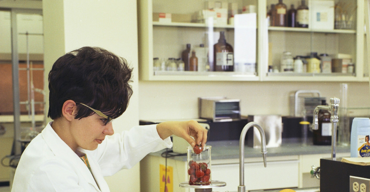 a woman in a white lab coat sitting at a counter in front of a sink