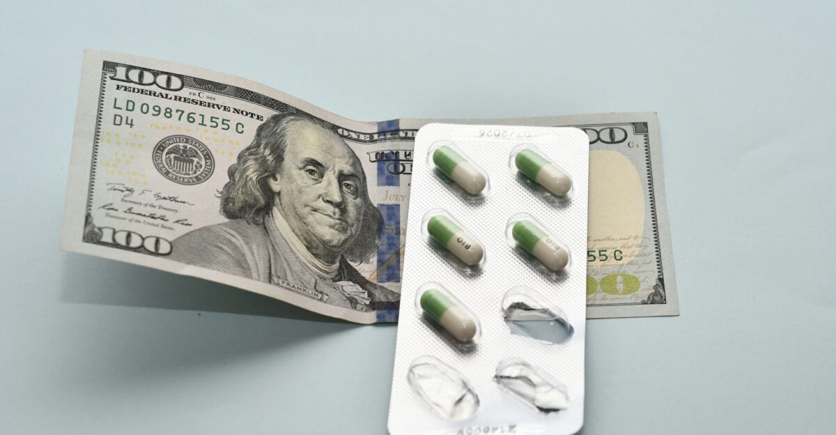 a pack of pills sitting on top of a hundred dollar bill