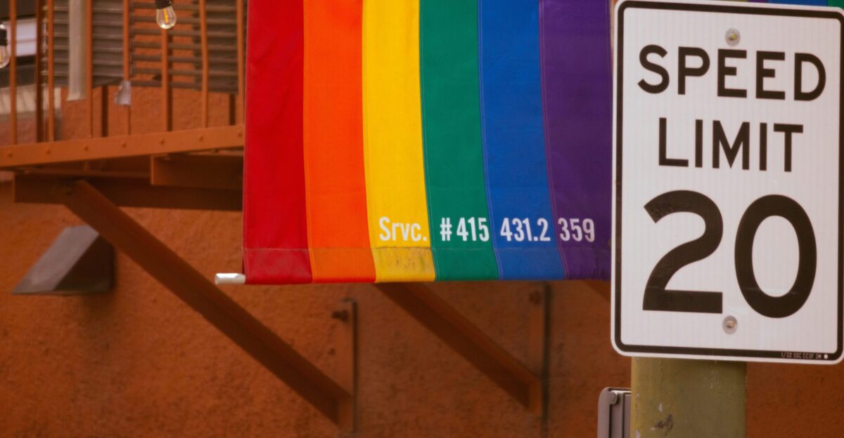 a speed limit sign next to a rainbow flag