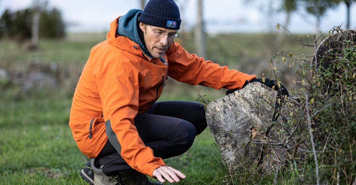 a man in an orange jacket leaning on a rock