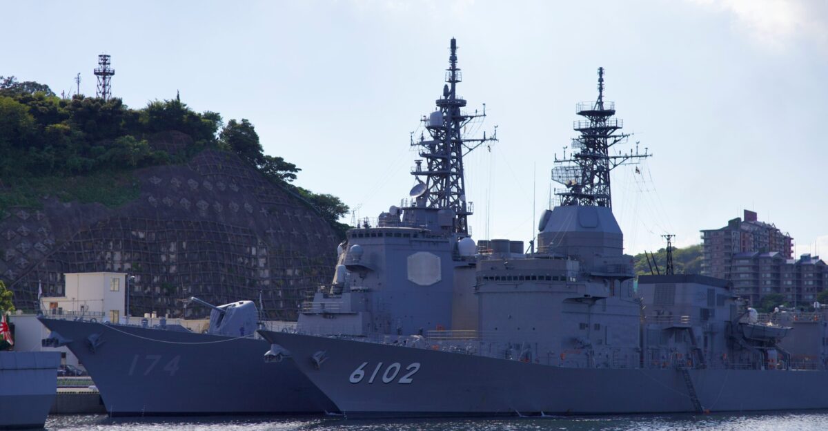 two navy ships are docked in a harbor