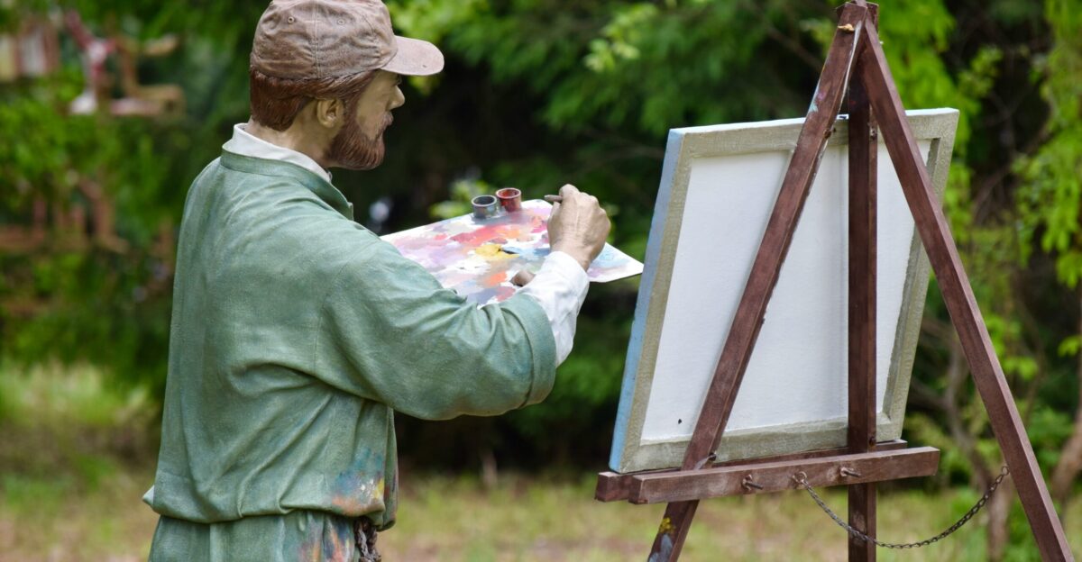 a statue of a man holding a paintbrush and painting a picture