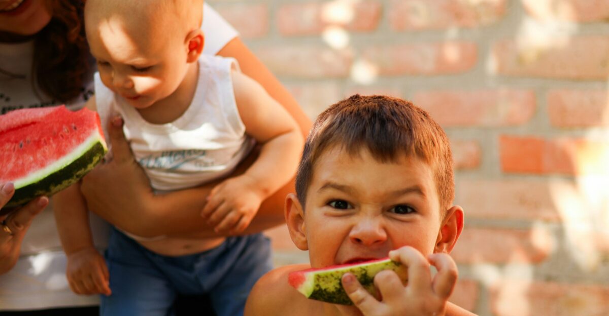 a young boy eating a piece of watermelon