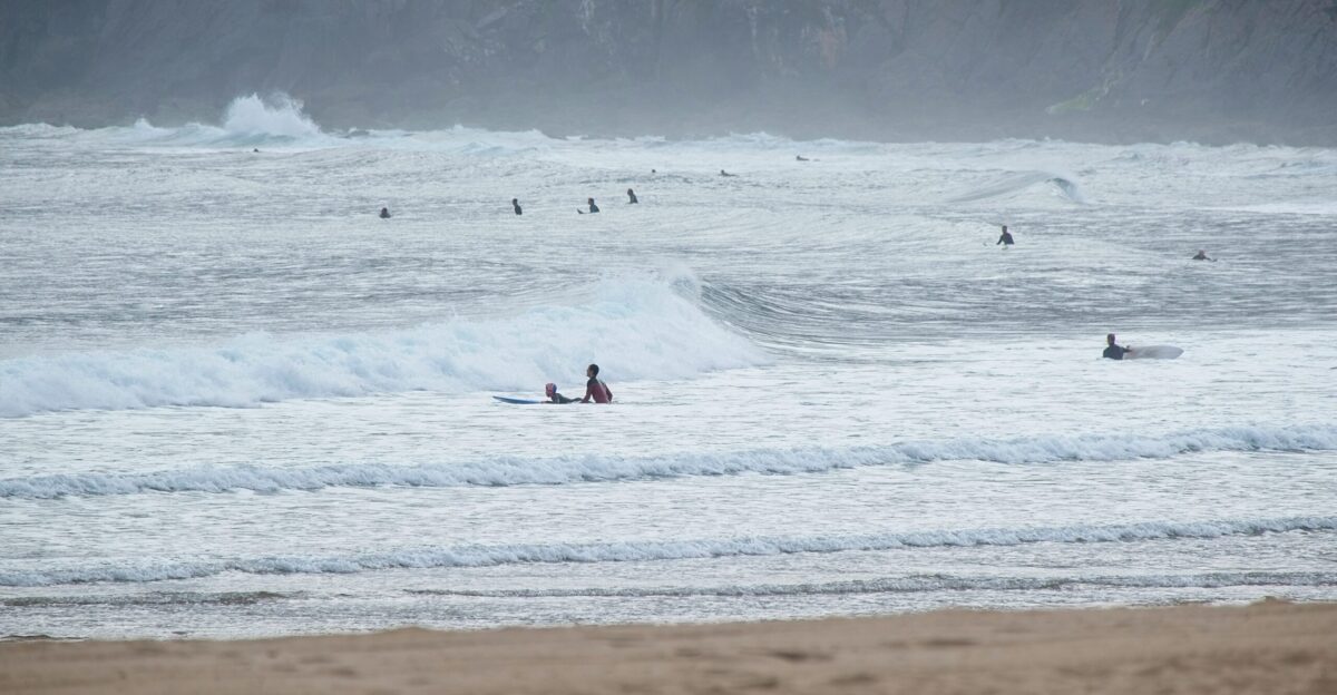 a group of people riding surfboards on top of a wave