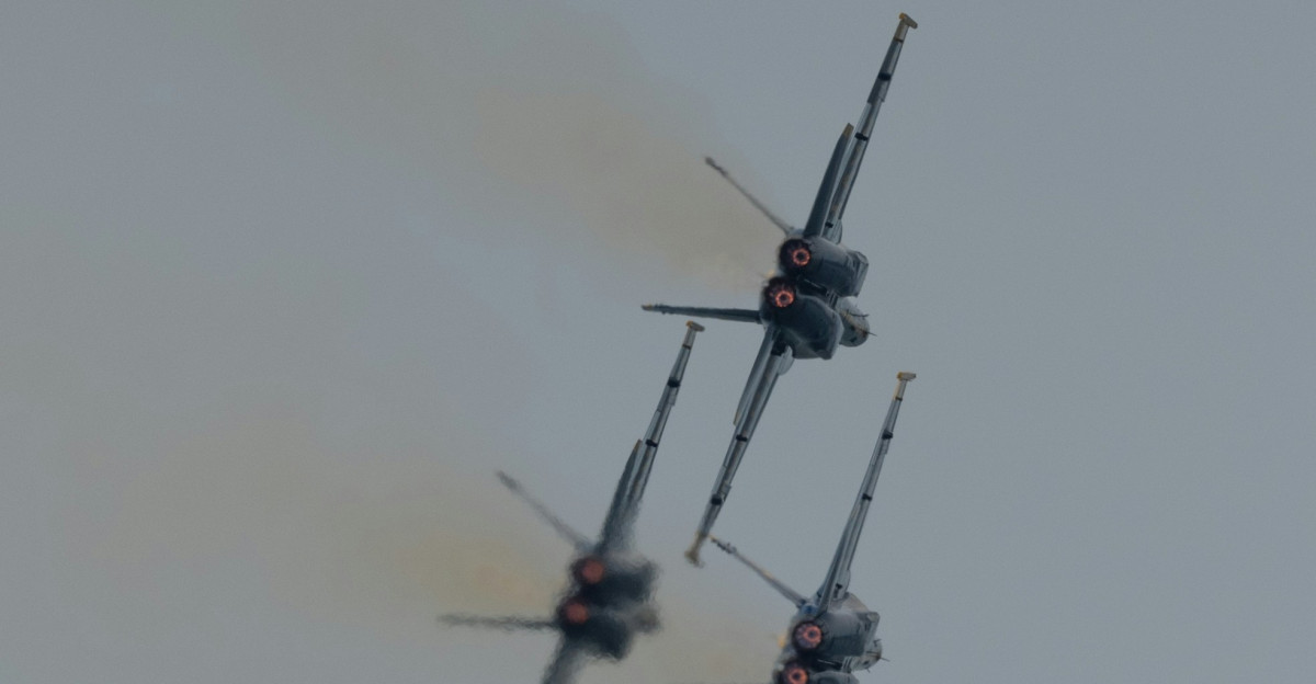 a group of fighter jets flying through a cloudy sky