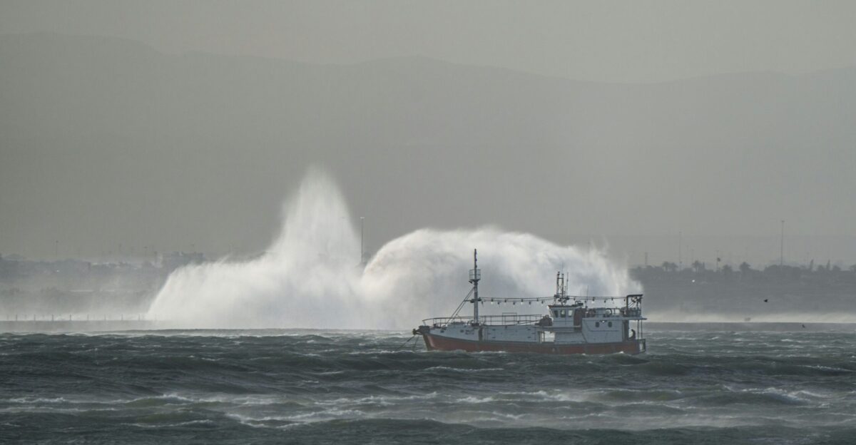 a boat in the water with a huge wave in the background