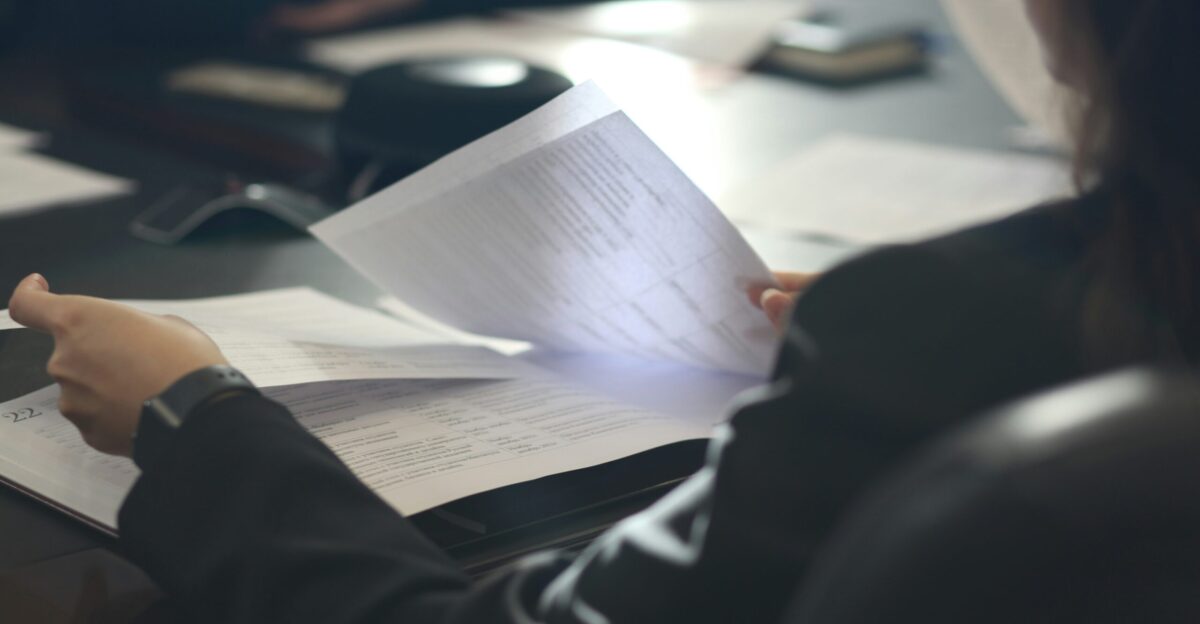 a woman sitting at a table reading a paper