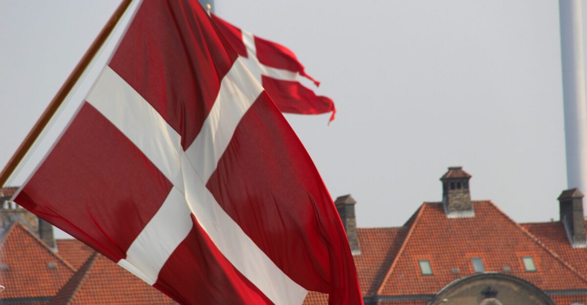 a red and white flag flying in front of a building