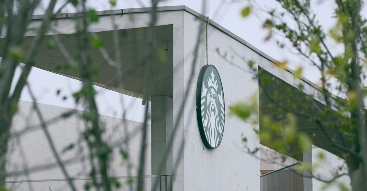 a starbucks sign is seen through the branches of a tree