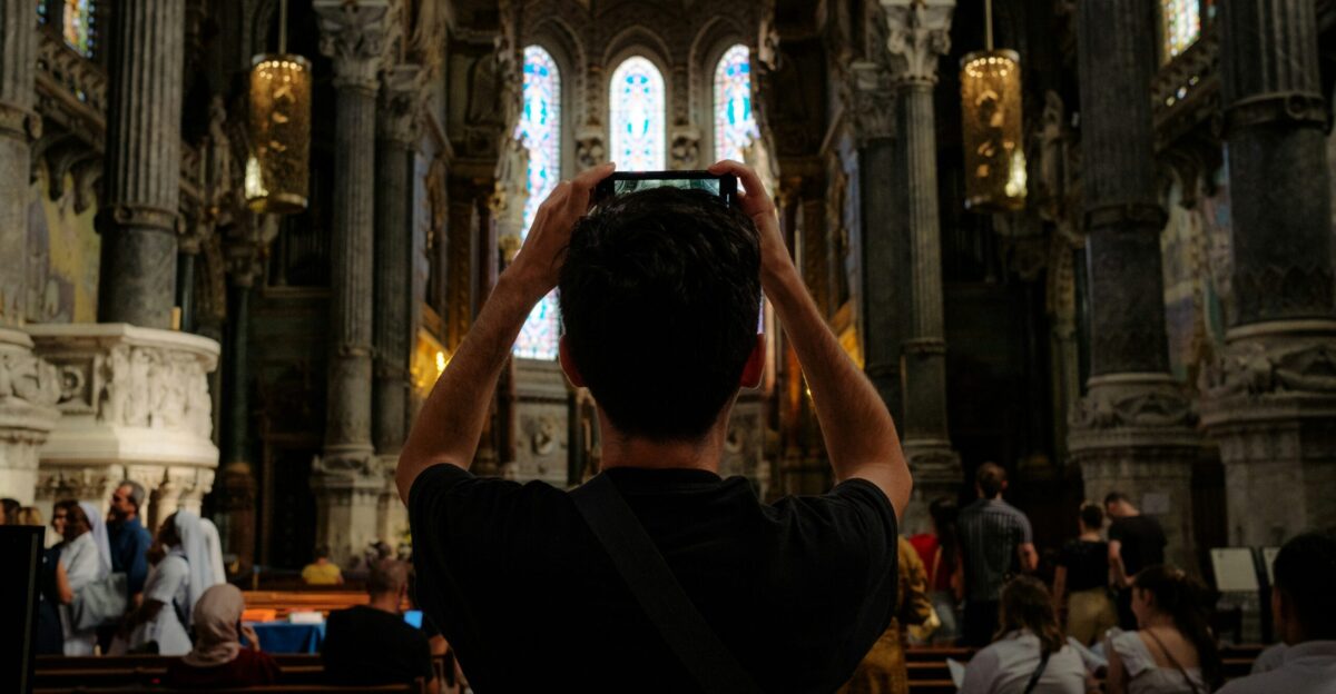 a man taking a picture of a church with his cell phone