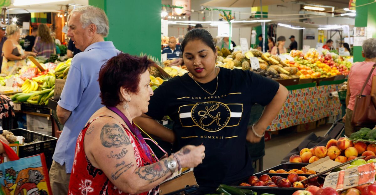 a group of people standing around a produce stand