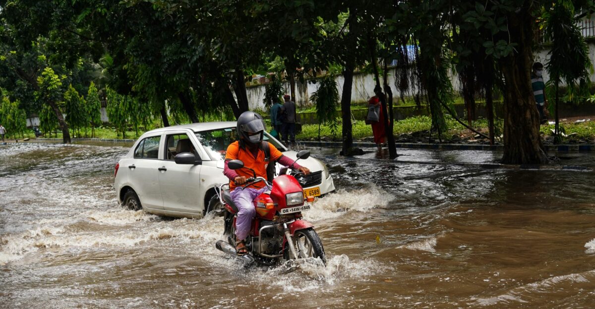 a man riding a motorcycle through a flooded street