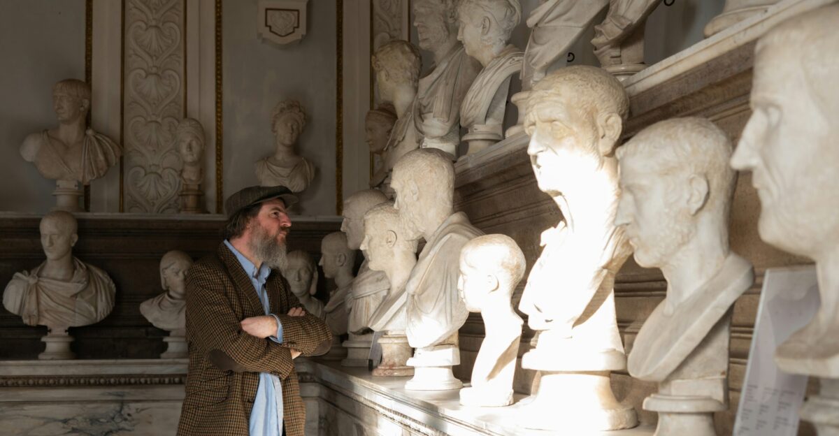a man standing next to a wall with statues on it