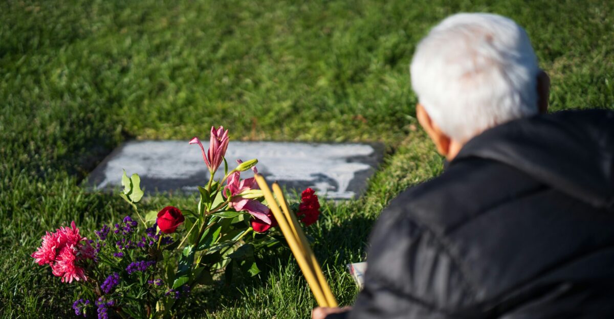 a man sitting in the grass next to flowers