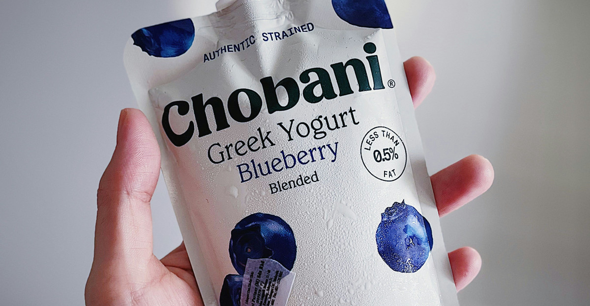 a hand holding a bottle of chobani greek yogurt blueberry