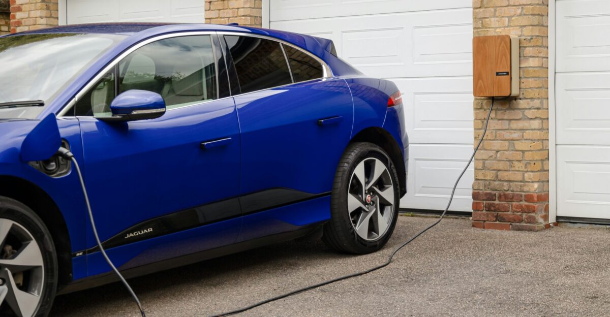 A blue electric car plugged in to a garage