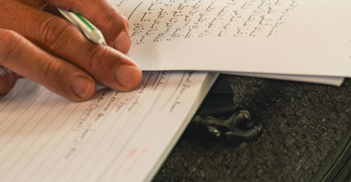 A person sitting at a table writing on a piece of paper