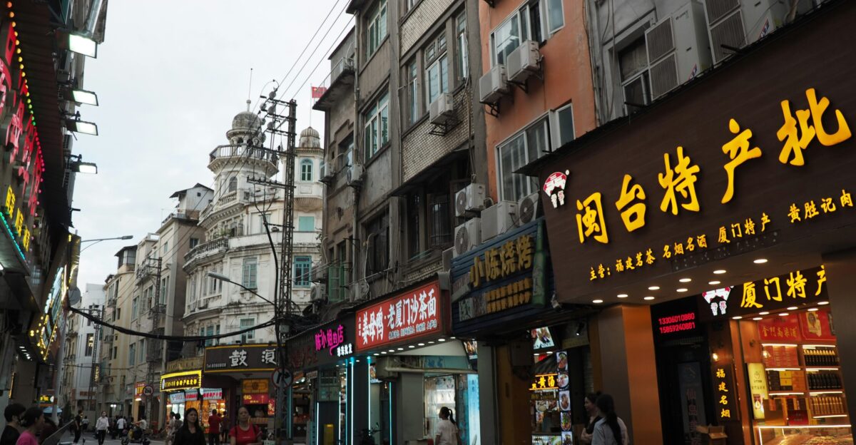 A group of people walking down a street next to tall buildings