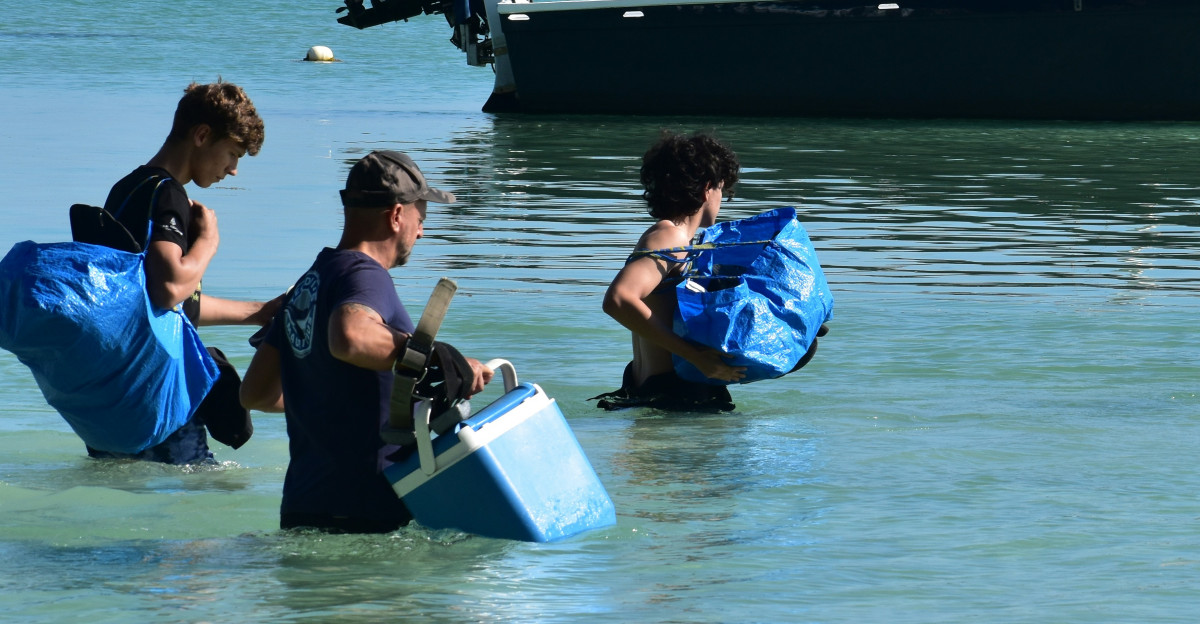 A group of people in the water with a boat in the background