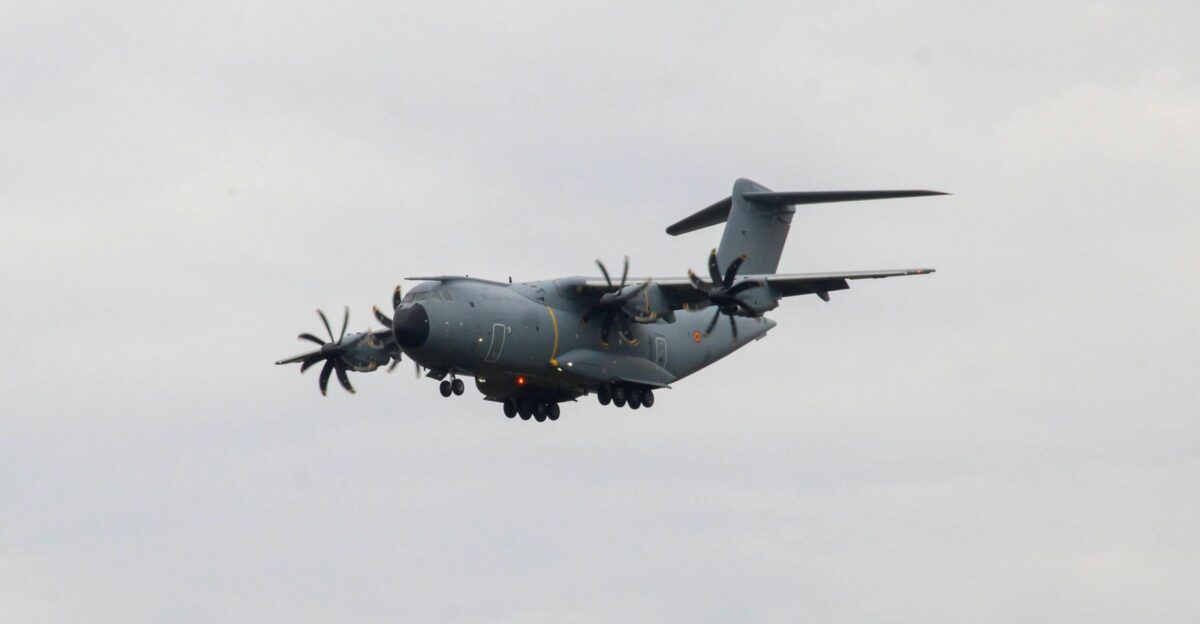 A large military plane flying through a cloudy sky