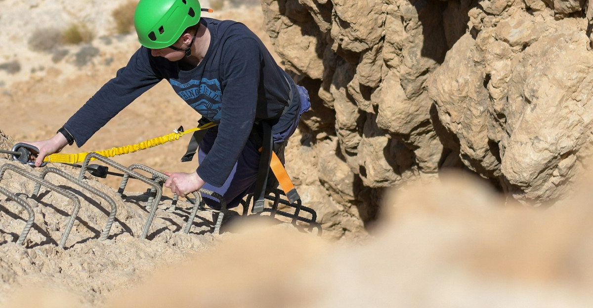 A man in a green helmet climbing up a mountain