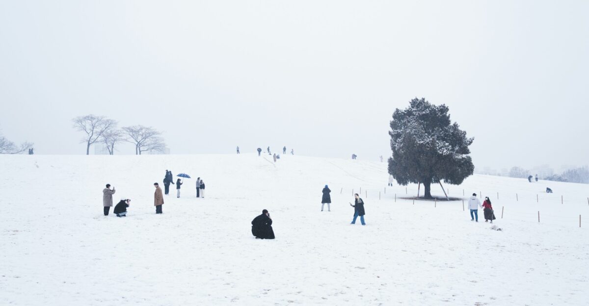 A group of people walking across a snow covered field