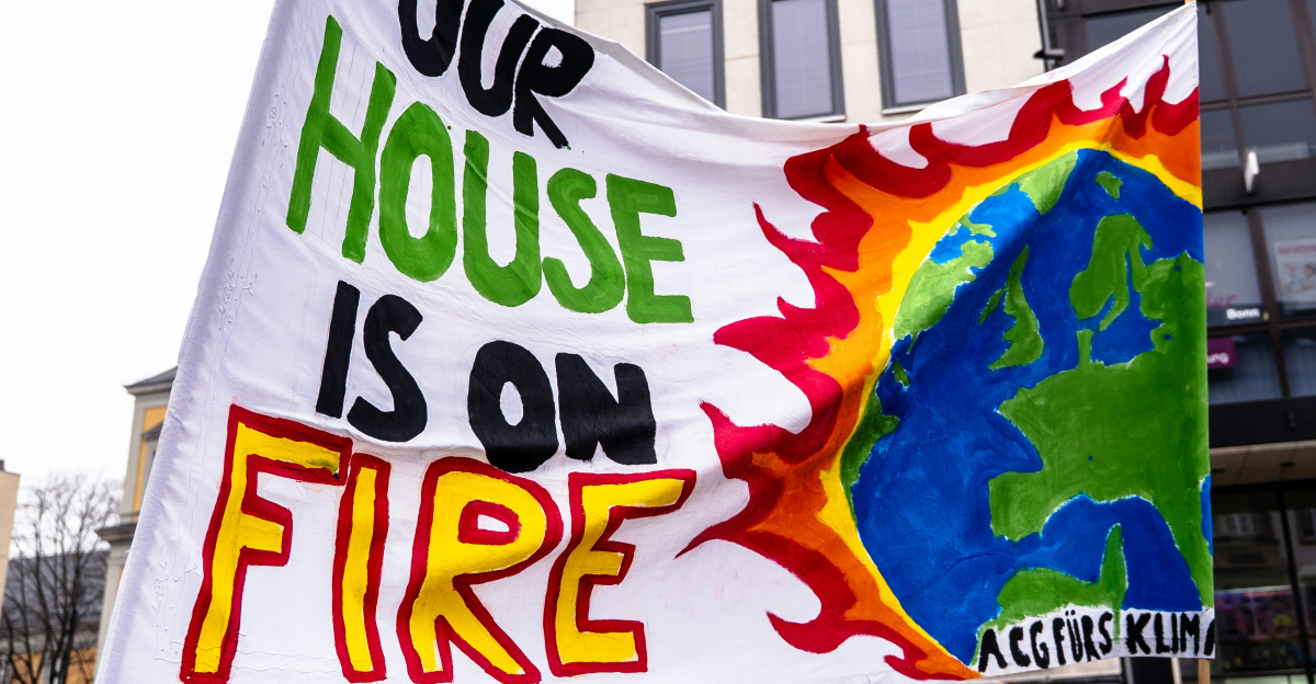 A group of people holding a sign that says one house is on fire