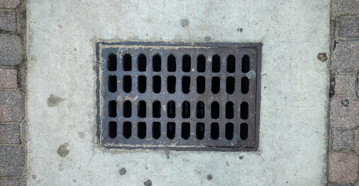 A grate on the side of a brick wall