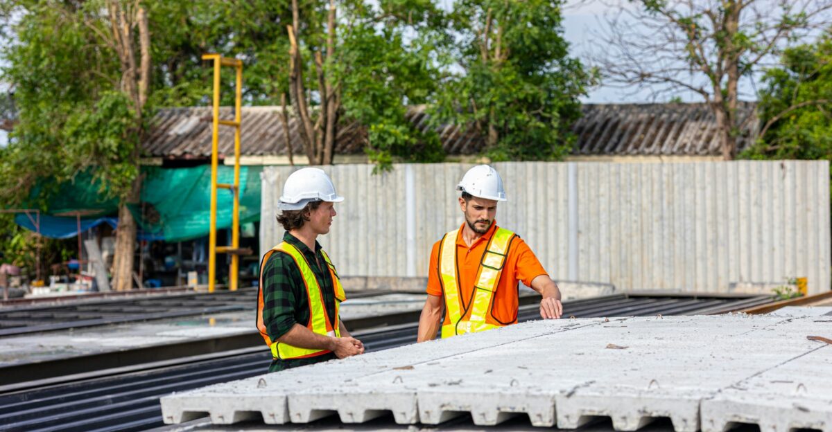 Construction workers inspect precast concrete slabs outdoors