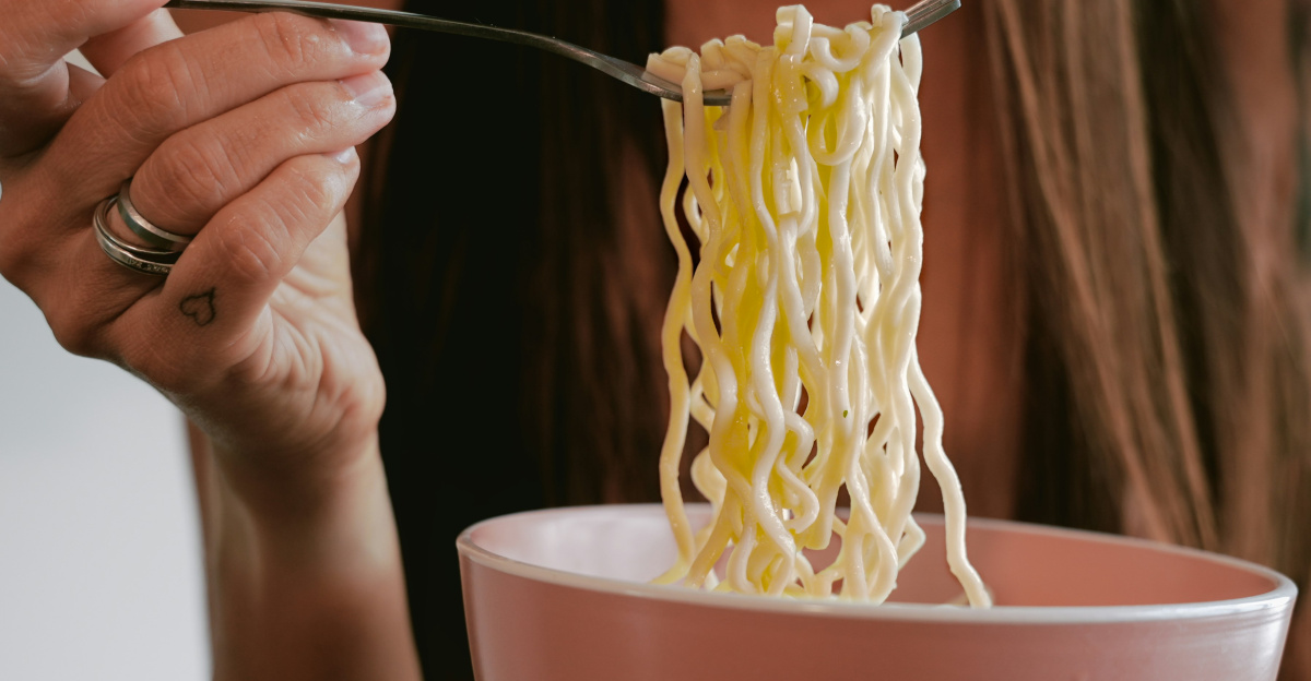 Woman eating noodles from a pink bowl.