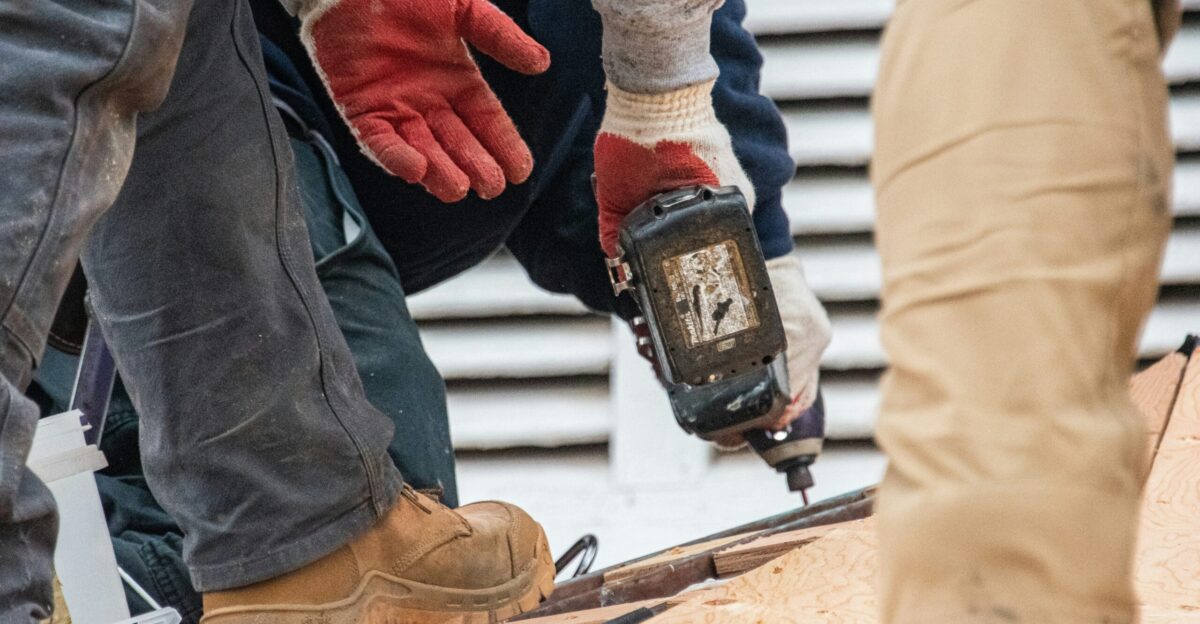 Workers are using a drill on a roof