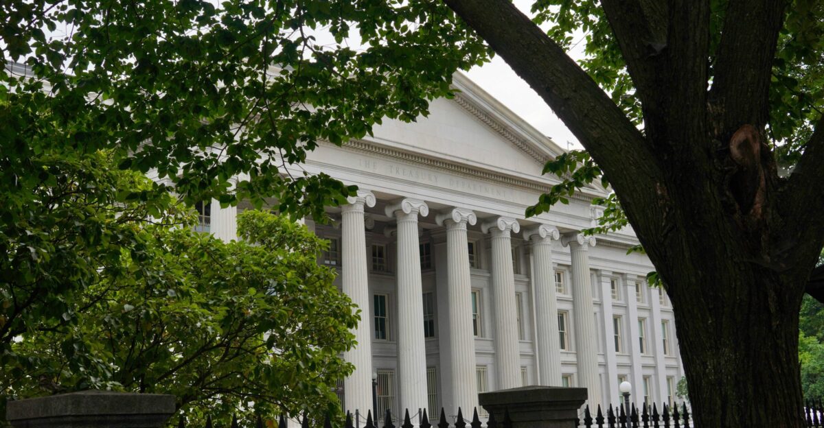 The white house is partially visible through trees