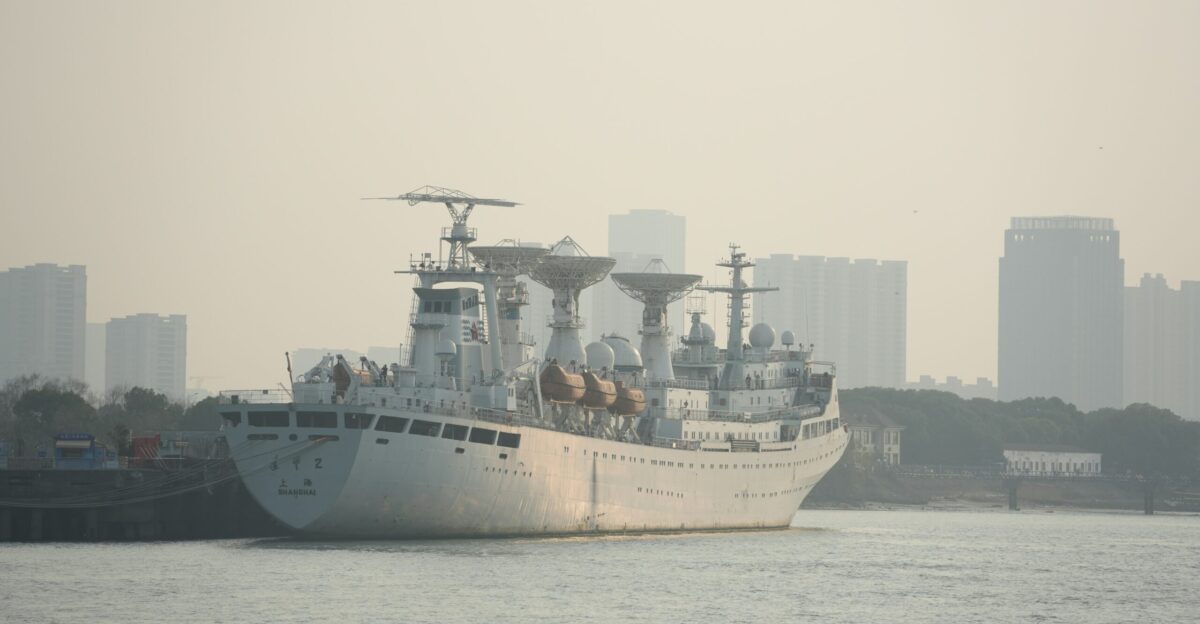 A white ship is docked in front of a city