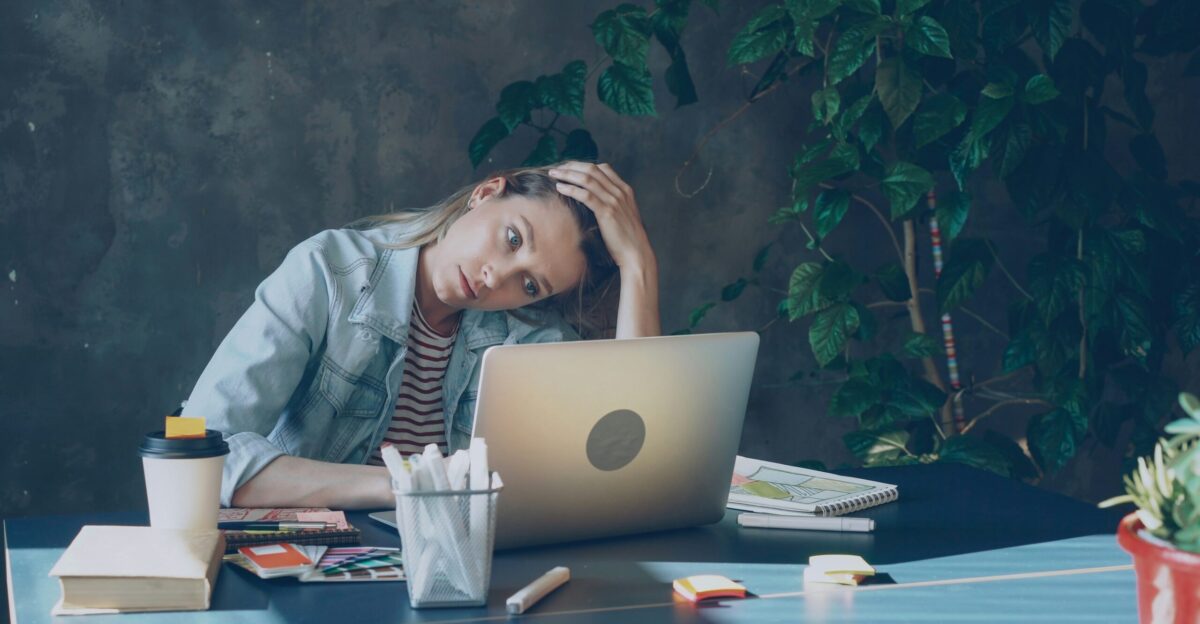A woman appears stressed while working on laptop