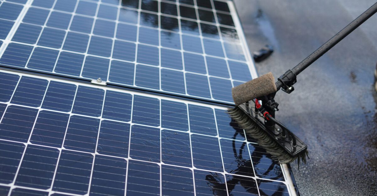Cleaning solar panels with a long handled brush