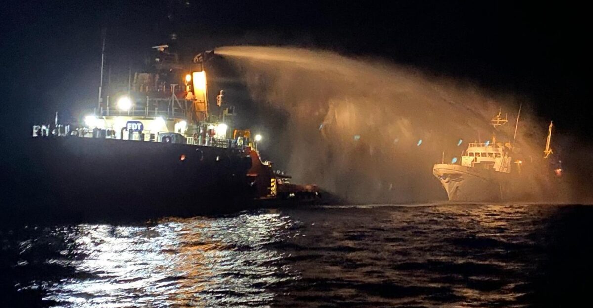 A tug vessel sprays water to extinguish a fire aboard a ship from the Gaza Freedom Flotilla during a nighttime emergency in May 2025
